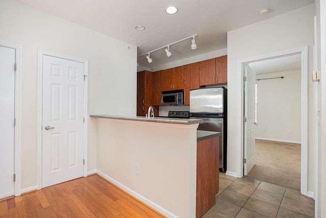 kitchen featuring appliances with stainless steel finishes, rail lighting, sink, kitchen peninsula, and a textured ceiling