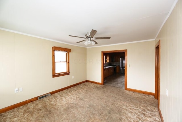 spare room featuring ceiling fan, ornamental molding, and carpet