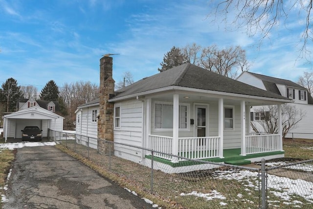 bungalow-style house with a garage, an outbuilding, and covered porch