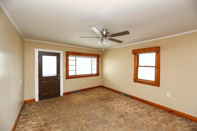 foyer entrance with crown molding, ceiling fan, and carpet flooring