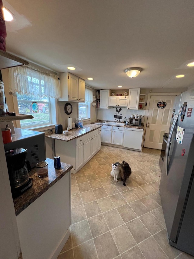 kitchen with stainless steel fridge, dishwasher, white cabinetry, light stone counters, and tasteful backsplash