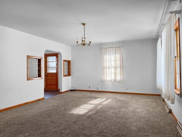 carpeted spare room featuring an inviting chandelier