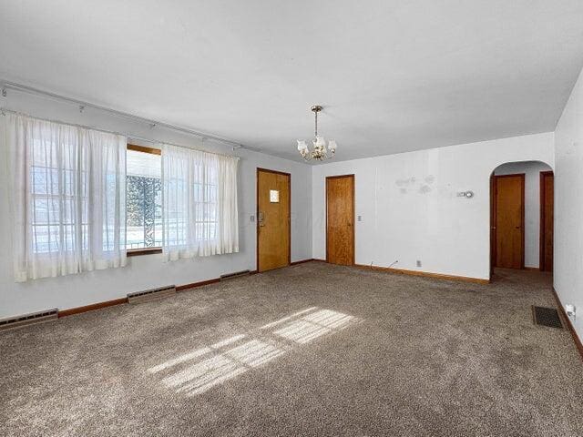 spare room with carpet and a notable chandelier