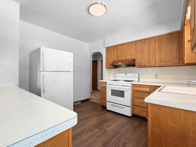 kitchen featuring tasteful backsplash, white appliances, dark hardwood / wood-style floors, and sink