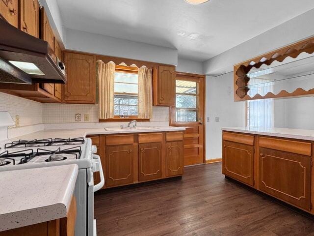 kitchen with dark wood-type flooring, decorative backsplash, sink, and white range with gas stovetop