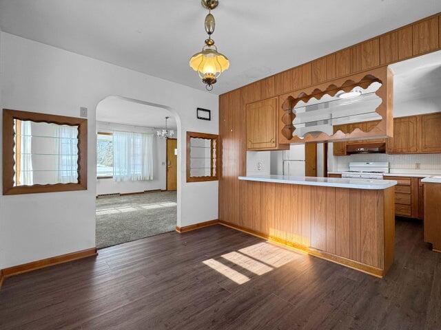 kitchen with pendant lighting, white appliances, dark hardwood / wood-style flooring, and kitchen peninsula