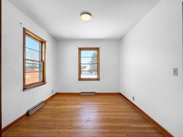 spare room featuring light hardwood / wood-style flooring, a healthy amount of sunlight, and baseboard heating