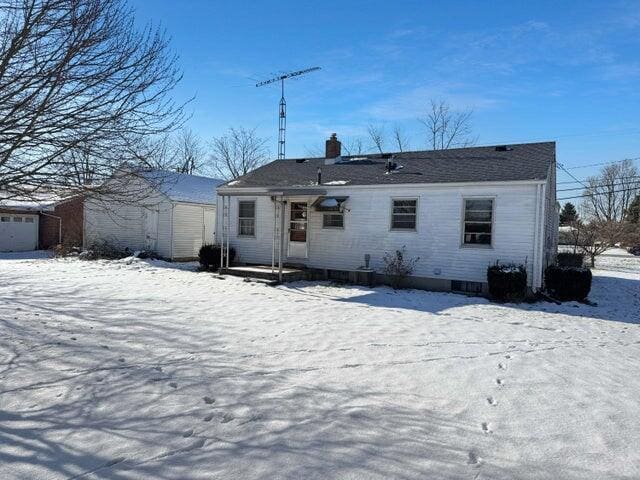 snow covered rear of property with a storage shed