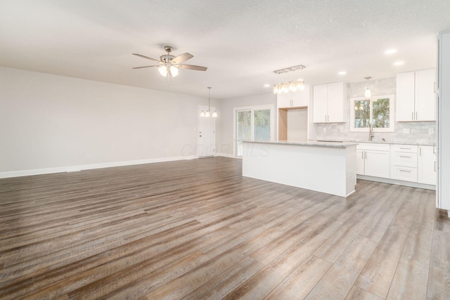 kitchen featuring white cabinetry, sink, a center island, and light wood-type flooring