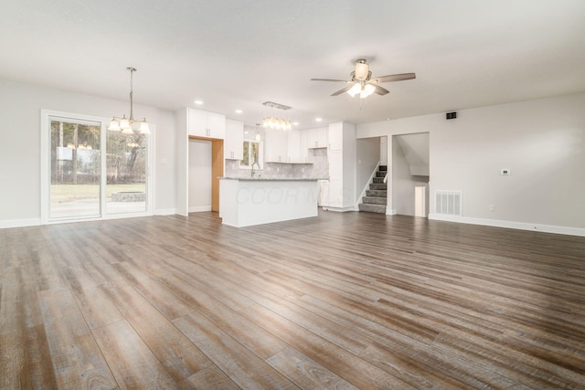 unfurnished living room featuring sink, ceiling fan with notable chandelier, and light hardwood / wood-style floors