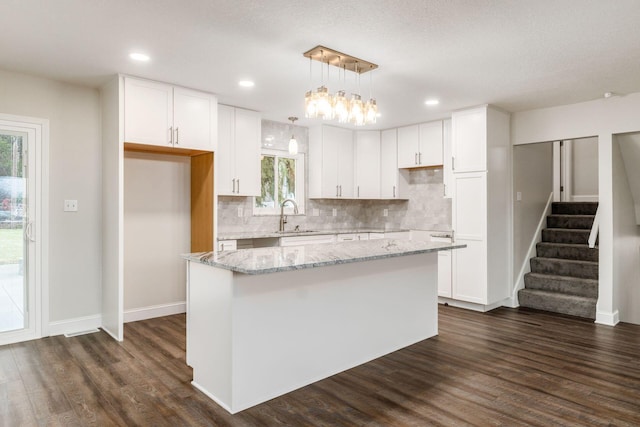 kitchen featuring white cabinetry, a center island, sink, and pendant lighting