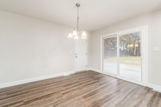 unfurnished dining area featuring hardwood / wood-style flooring and a chandelier