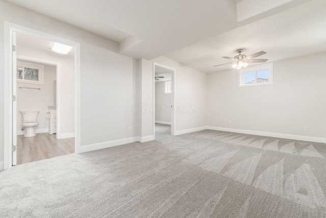 basement featuring ceiling fan and light colored carpet