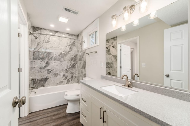 full bathroom with tiled shower / bath combo, vanity, wood-type flooring, and toilet