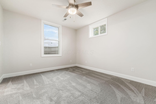 carpeted empty room with ceiling fan and plenty of natural light