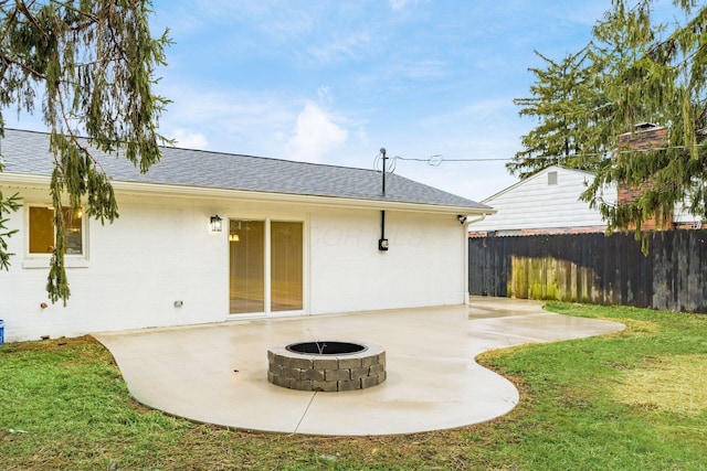 rear view of property with a yard, a fire pit, and a patio area