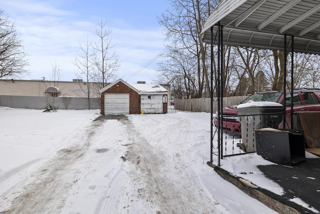 yard layered in snow with a garage and an outdoor structure