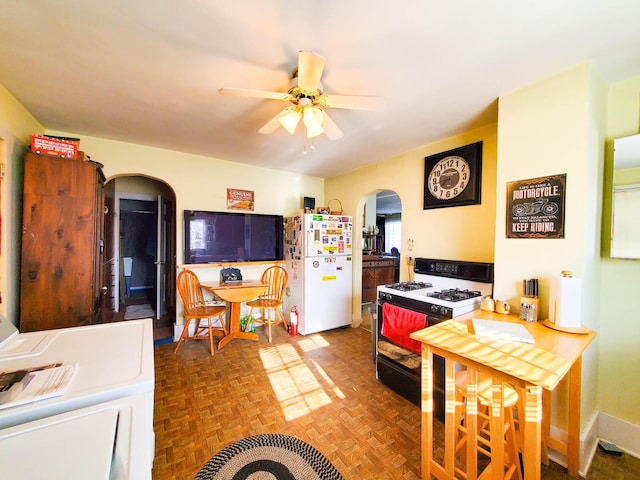 kitchen with parquet flooring, gas stove, white fridge, ceiling fan, and washer / clothes dryer