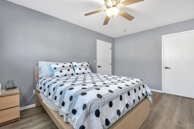 bedroom with light wood finished floors, a ceiling fan, and baseboards