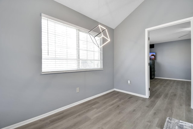 unfurnished dining area featuring baseboards, vaulted ceiling, and wood finished floors