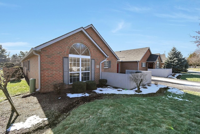 view of front facade featuring brick siding, a front lawn, and fence