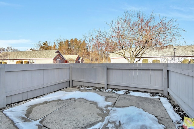 snow covered patio with a fenced backyard