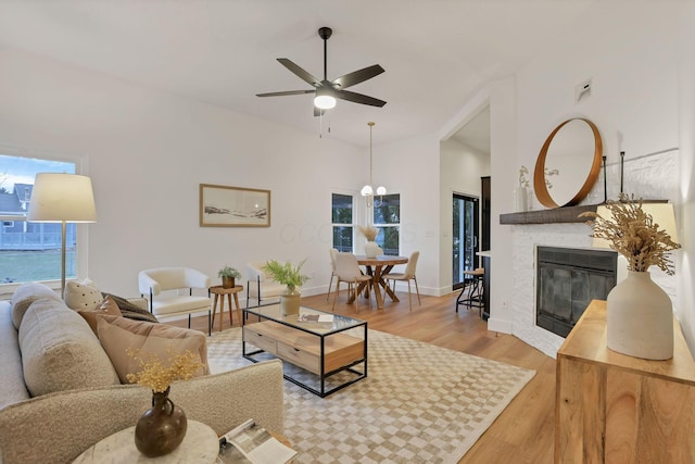 living room with ceiling fan, vaulted ceiling, and light wood-type flooring