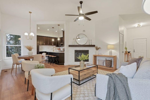 living room featuring ceiling fan with notable chandelier and light hardwood / wood-style flooring