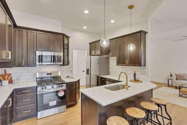 kitchen with pendant lighting, sink, light hardwood / wood-style floors, and appliances with stainless steel finishes