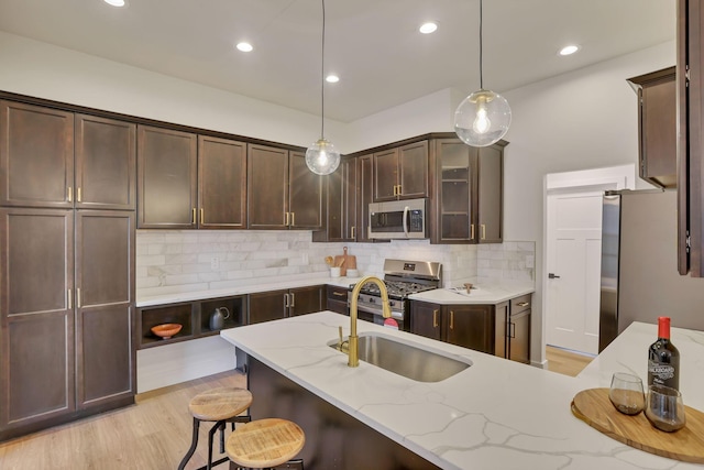 kitchen featuring appliances with stainless steel finishes, tasteful backsplash, sink, hanging light fixtures, and light stone countertops