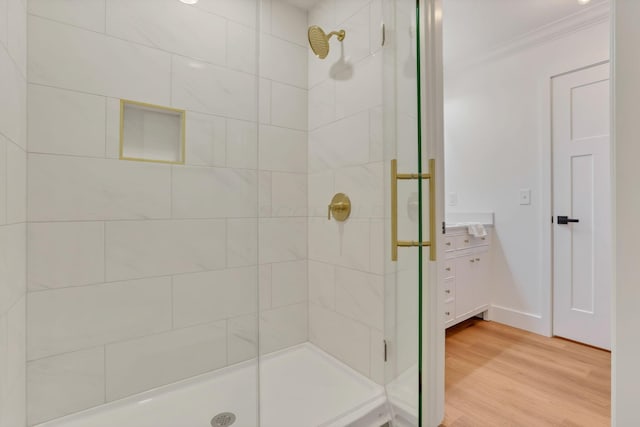 bathroom featuring vanity, crown molding, wood-type flooring, and walk in shower