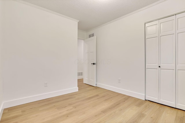 unfurnished bedroom with crown molding, a closet, light hardwood / wood-style flooring, and a textured ceiling