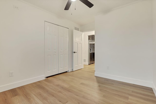 unfurnished bedroom with crown molding, ceiling fan, light hardwood / wood-style floors, and a closet