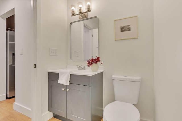 bathroom featuring vanity, wood-type flooring, and toilet