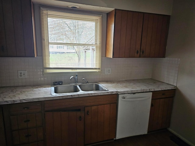 kitchen featuring a sink, decorative backsplash, light countertops, and dishwasher