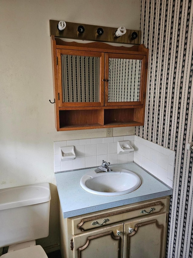 half bath with toilet, tasteful backsplash, and vanity