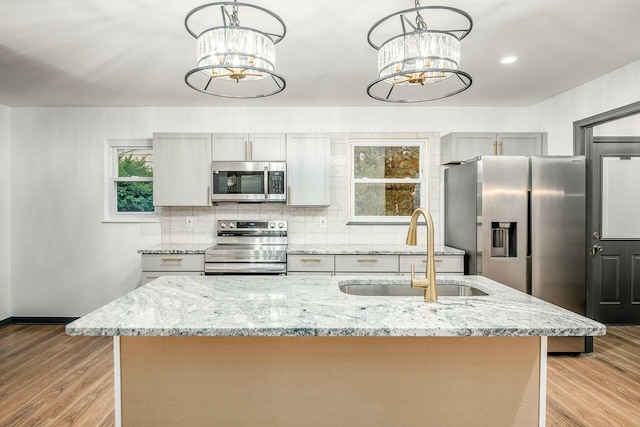 kitchen with stainless steel appliances, decorative light fixtures, sink, and a notable chandelier