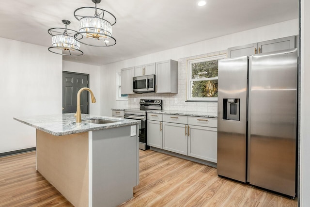 kitchen with a kitchen island with sink, sink, gray cabinetry, and appliances with stainless steel finishes