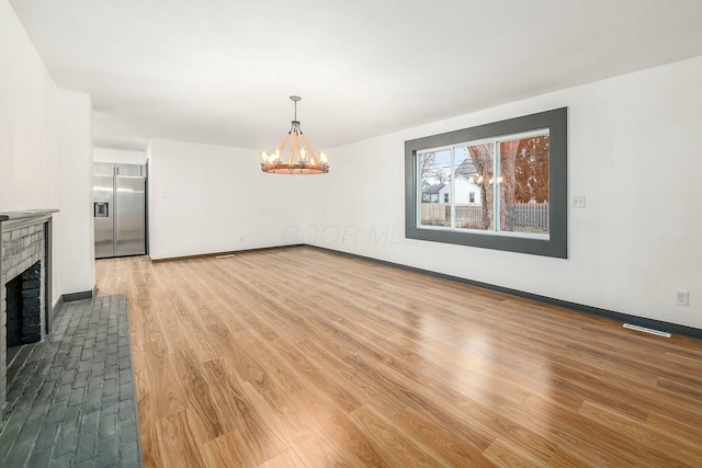 interior space with a fireplace, a chandelier, and light wood-type flooring