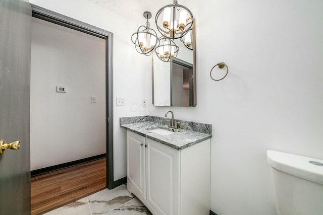 bathroom featuring vanity, an inviting chandelier, and toilet