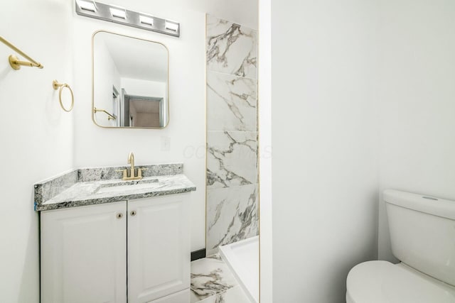 bathroom featuring vanity, toilet, and tiled shower