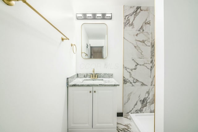 bathroom featuring a tile shower and vanity