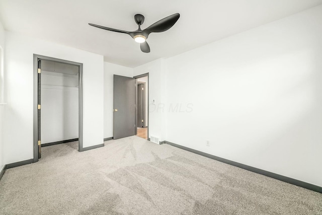 unfurnished bedroom featuring light carpet, a closet, and ceiling fan