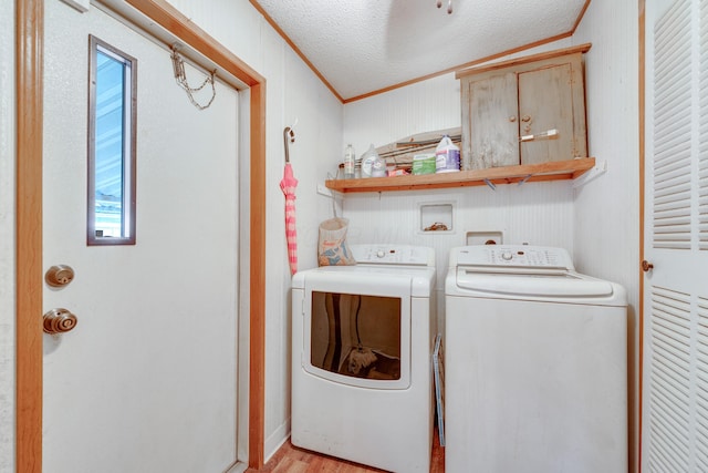 laundry room featuring cabinets, washer and clothes dryer, crown molding, a textured ceiling, and light wood-type flooring