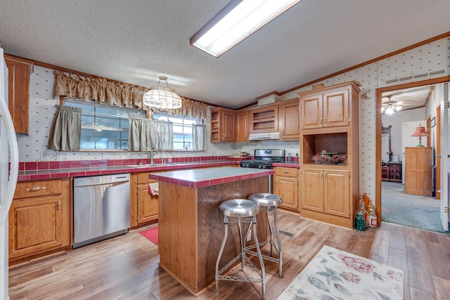 kitchen featuring lofted ceiling, stainless steel appliances, a center island, tile counters, and a textured ceiling