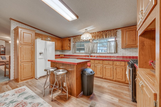 kitchen featuring a kitchen island, lofted ceiling, sink, white fridge with ice dispenser, and stainless steel gas range