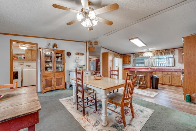 carpeted dining space with ornamental molding, vaulted ceiling, washer and dryer, and a textured ceiling