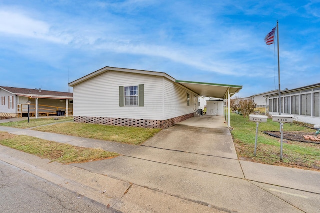 manufactured / mobile home featuring a front lawn and a carport