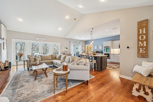 living room featuring vaulted ceiling, light hardwood / wood-style flooring, and a wealth of natural light