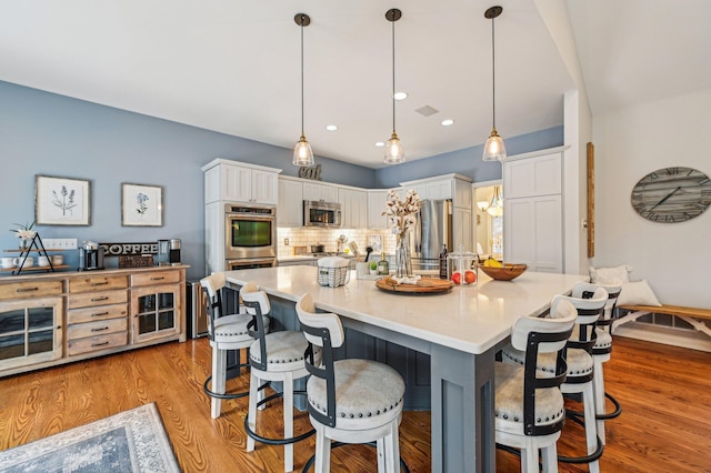 kitchen with stainless steel appliances, pendant lighting, white cabinets, and a kitchen breakfast bar